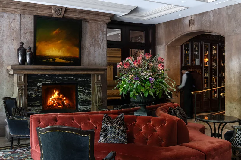 Armchairs and tables beside the fireplace in the Bacchus lounge.