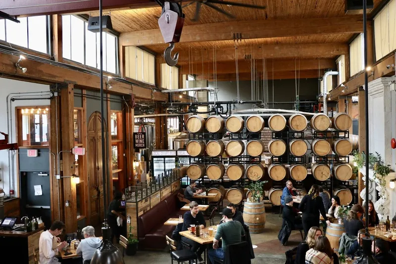 Tables and stacked barrels in the high-ceilinged dining room at Belgard Kitchen.