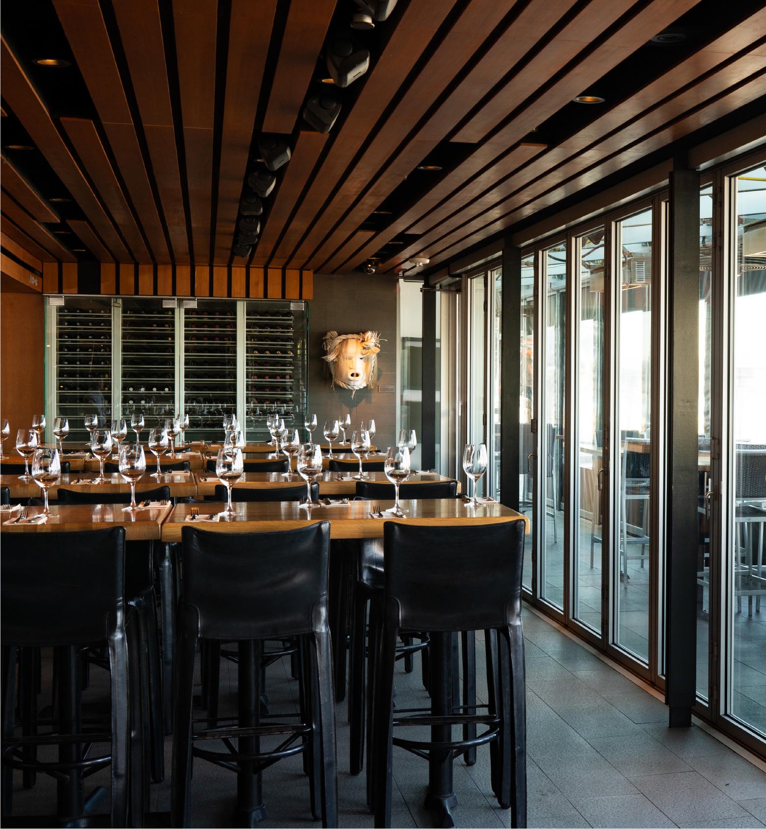 Dining tables, dark chairs and large windows inside Cactus Club Cafe English Bay.