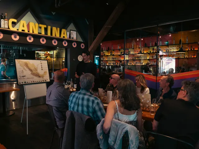 Guests attending an agave workshop inside Alimentaria Mexicana's cantina, with its bottle shelves and CANTINA sign behind them.