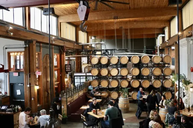 Tables and stacked barrels in the high-ceilinged dining room at Belgard Kitchen.