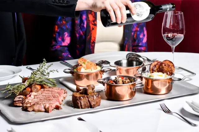 Sliced steak and side dishes served at a table at Black and Blue.