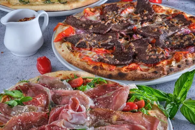 Pizzas topped with meat and tomatoes at Bonta Italian Ristorante.