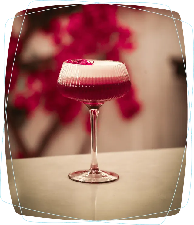 A ruby-red cocktail with a pale foam top in a stemmed glass, pictured on Cavo's website.