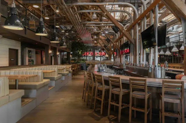 Bar seating and tables beneath exposed beams at Craft Beer Market False Creek.