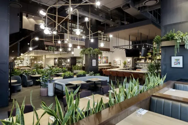 Tables, booths and plants inside Earls Test Kitchen.