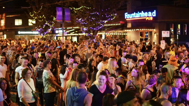 A nighttime crowd outside The Fountainhead Pub beneath its illuminated sign.