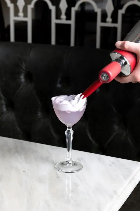 A pale purple cocktail being topped with foam at Homer St. Cafe and Bar.