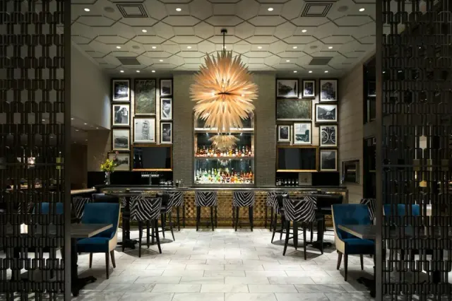 Restaurant dining room with framed pictures and a large pendant light.