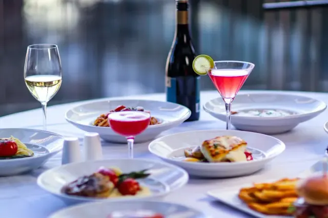 Plated dishes, wine and a cocktail on a restaurant table.