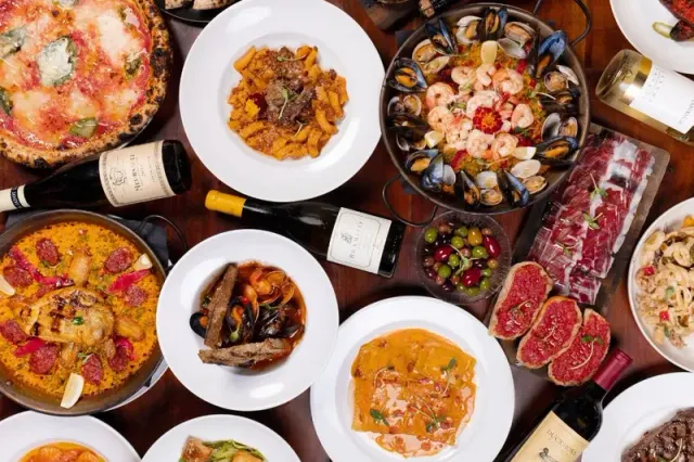 Pizzas, pasta and other dishes arranged across a table.