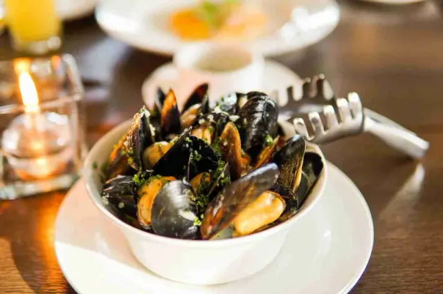 A bowl of mussels served on a restaurant table.