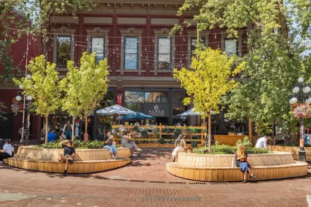 Brick restaurant building with outdoor seating and trees.