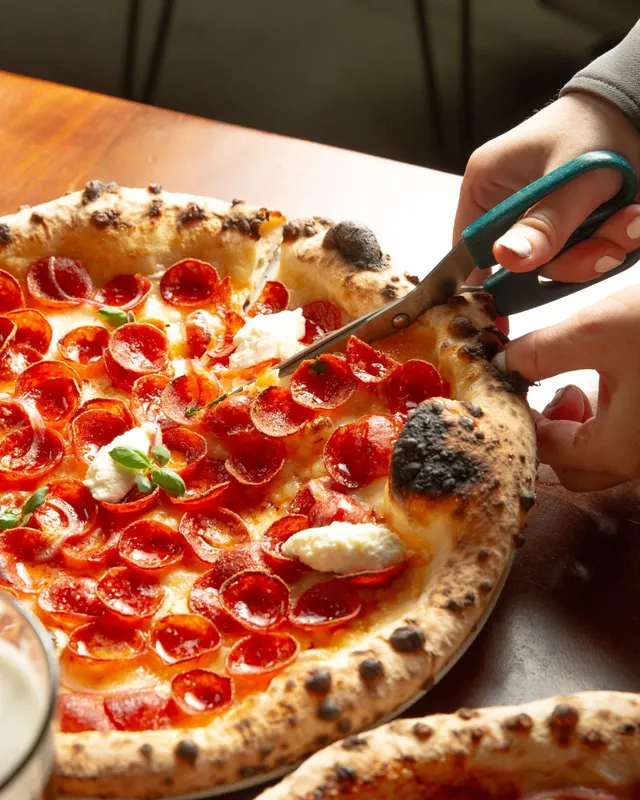 Pizza being cut with scissors, from Social Corner’s official website.