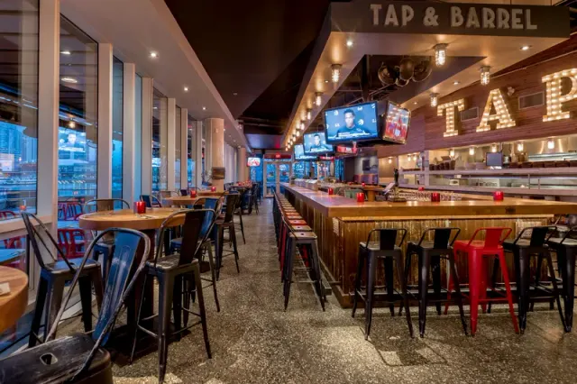 Tap and Barrel interior with a long bar, tall windows and tables.