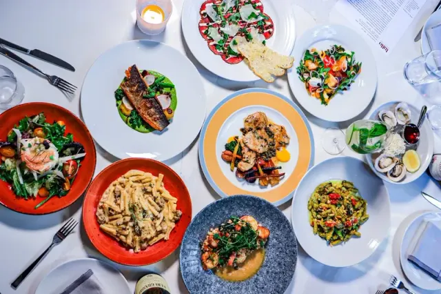 Pasta and other dishes arranged across a white-clothed table.