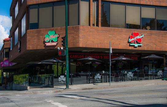 Carlos O'Bryan's Kitsilano exterior with branded shamrock signs and a street-side patio.