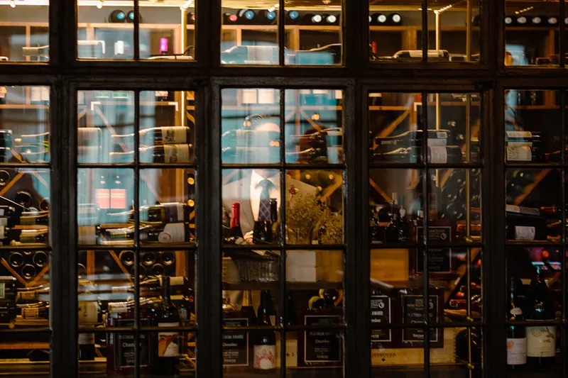 Wine storage and tables visible through glass at Chambar.