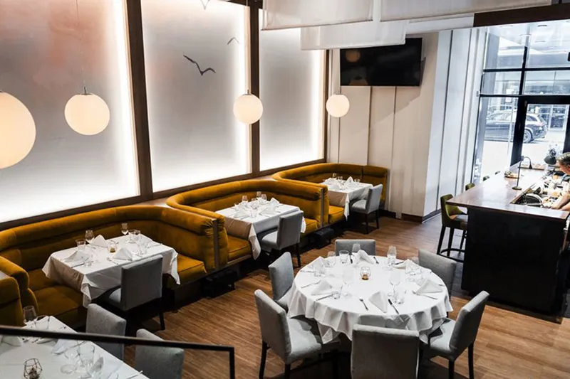 Set tables and upholstered seating in a bright dining room at Coast.