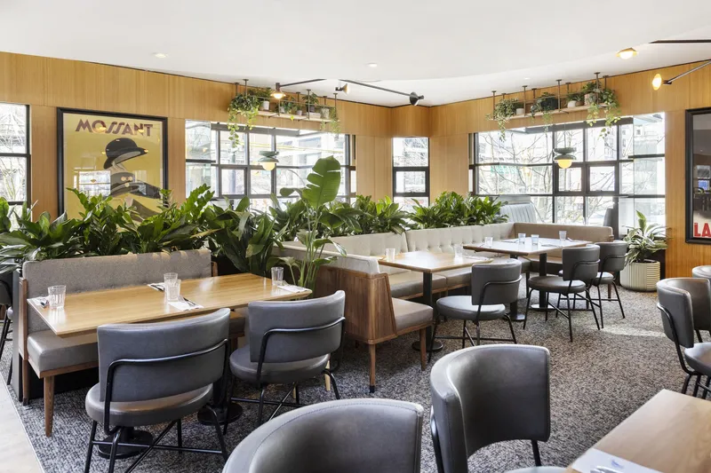 Dining tables and plants beside the windows at Earls Robson.