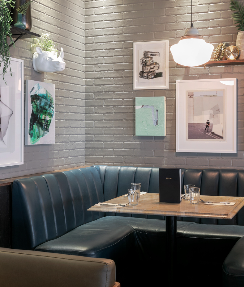 A dining booth with artwork and pendant lighting at Earls Yaletown.