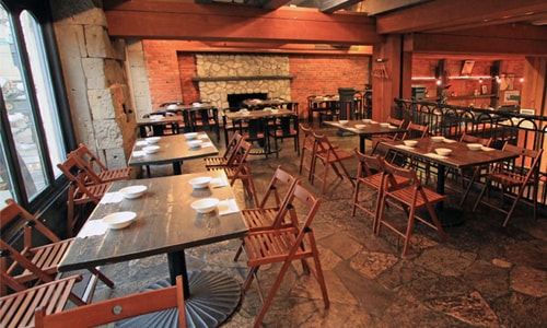 Wooden tables and chairs in the brick dining room at Guu with Otokomae.