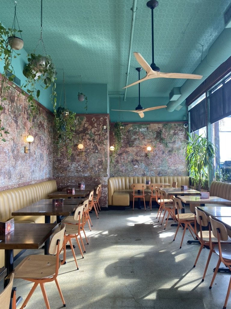 Havana dining room with turquoise ceiling, hanging plants and wooden tables.