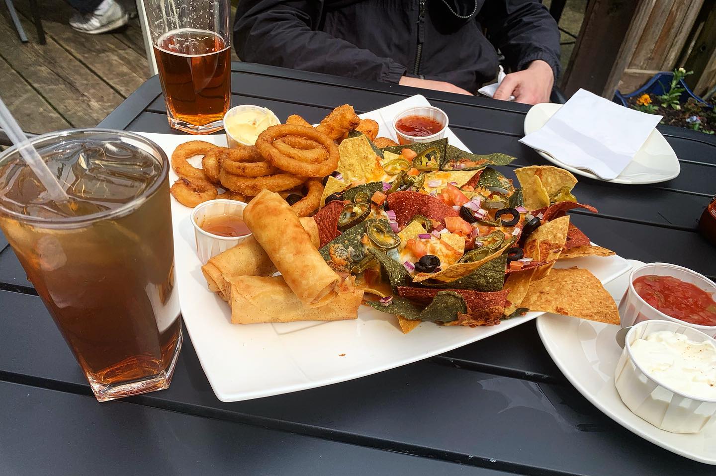 A sharing platter of nachos, onion rings and other appetizers on a patio table at The Junction.