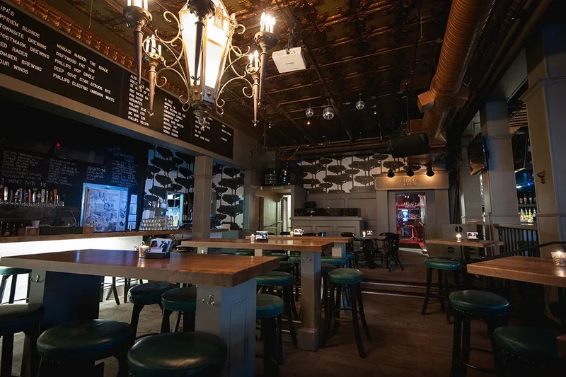 Tables and bar stools beneath hanging lights at The Lamplighter.