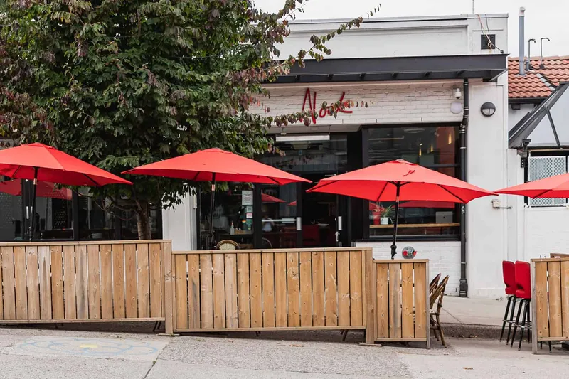 Restaurant exterior with a fenced patio and red umbrellas.
