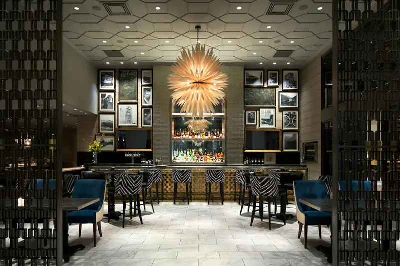 Restaurant dining room with framed pictures and a large pendant light.