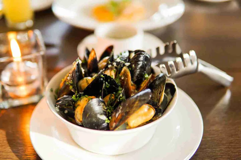A bowl of mussels served on a restaurant table.
