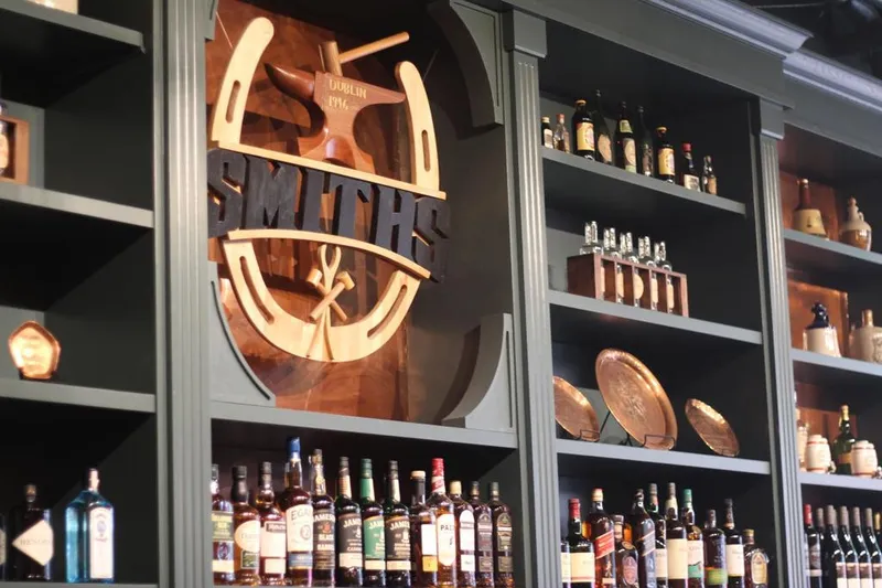 Bar shelves with bottles and a mounted Smith’s sign.