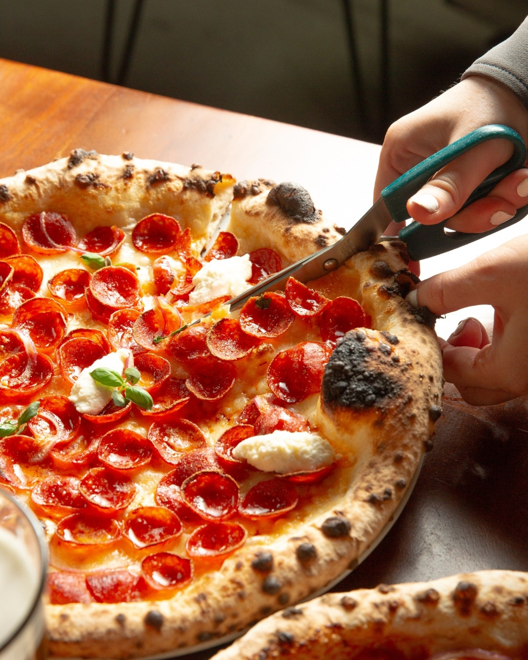 Pizza being cut with scissors, from Social Corner’s official website.