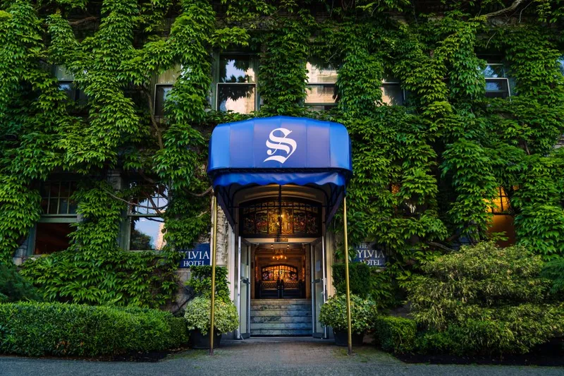 Hotel entrance with a blue canopy surrounded by an ivy-covered facade.