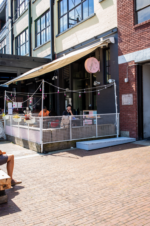 Tacofino Yaletown's street-side patio and entrance beneath its pink sign.