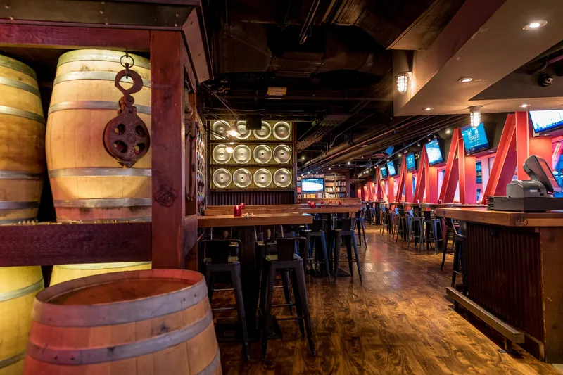 Pub interior with wooden barrels, tables and bar seating.
