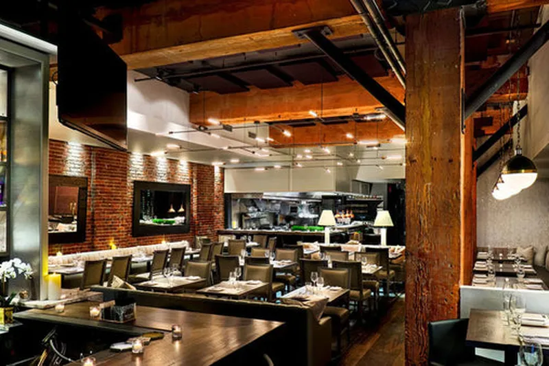 Restaurant dining room with exposed timber beams and set tables.